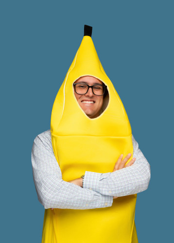 Smiling man wearing glasses and a bright yellow banana costume with his arms crossed.