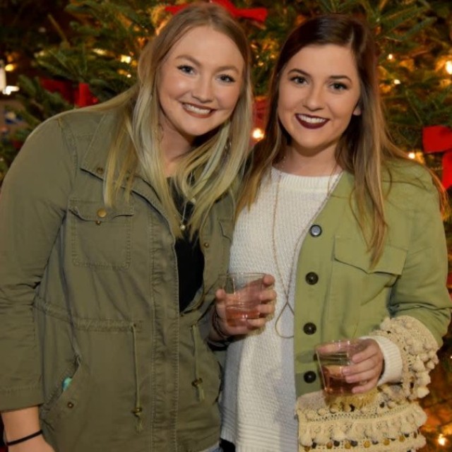 Two friend girls drinking wine at City Market’s holiday event