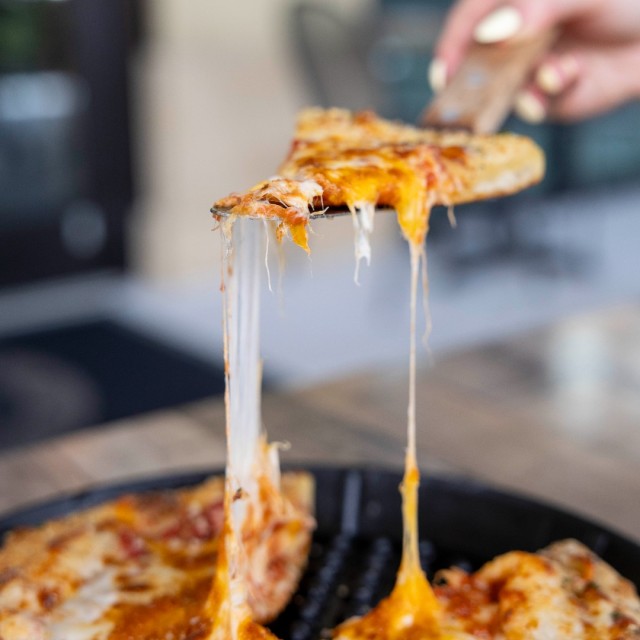 A slice of pizza lifted from a pan with a spatula