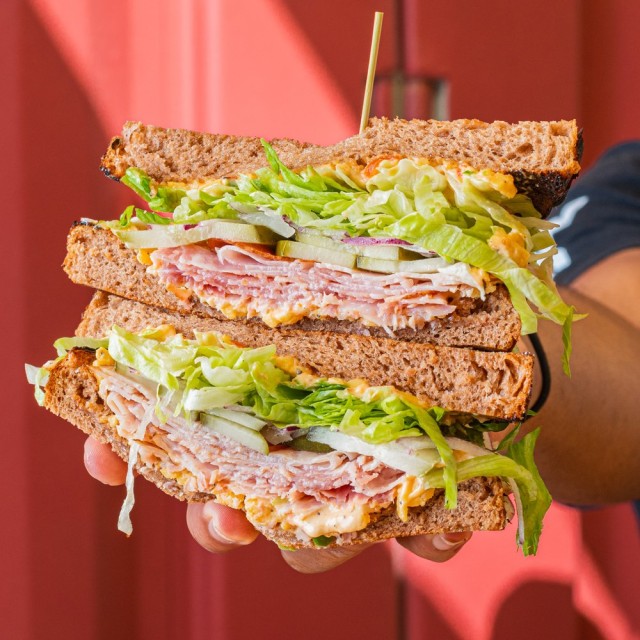 A person holding a highly stacked sandwich