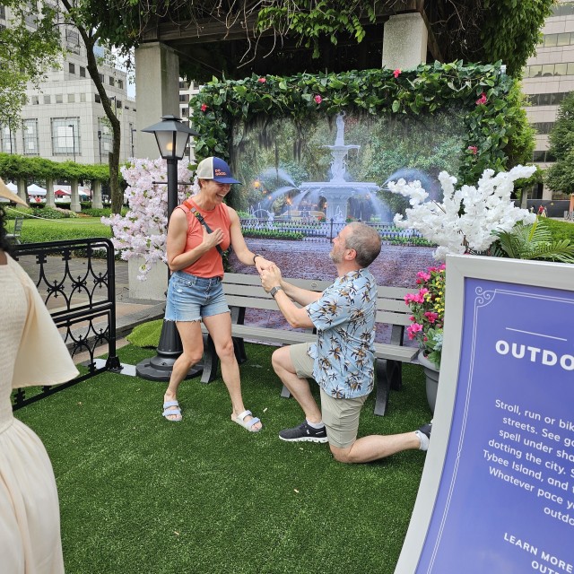 a man recreating a his proposal to a woman in front of a backdrop