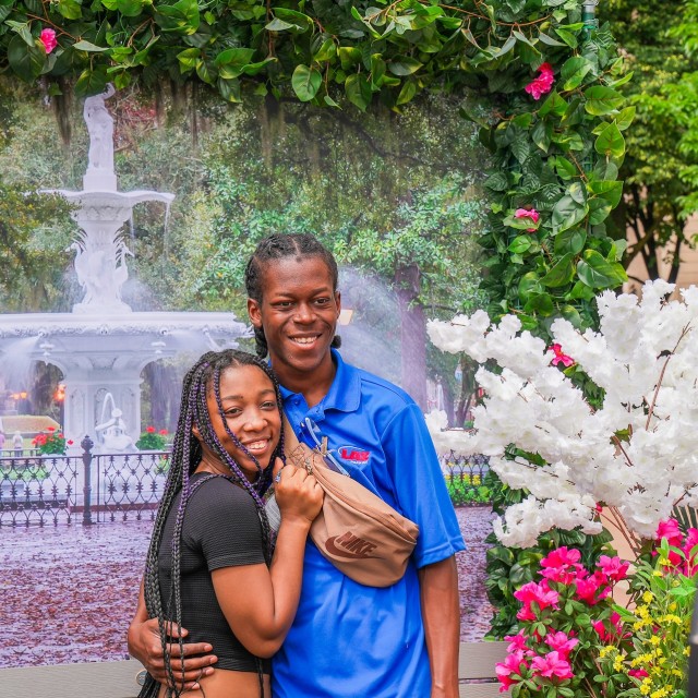 a couple in front of a backdrop taking a photo