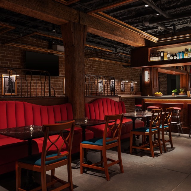 A lounge bar with red velvet couches.