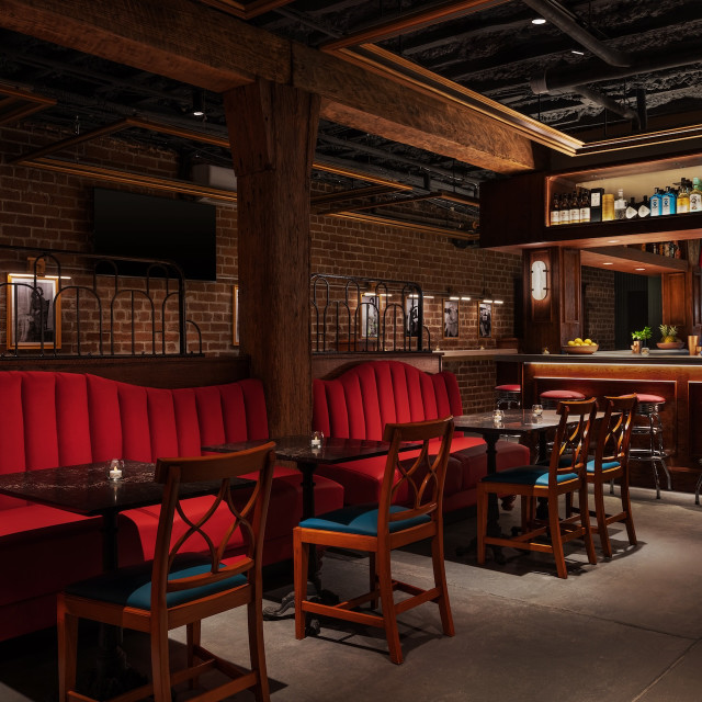 A lounge bar with red velvet couches.
