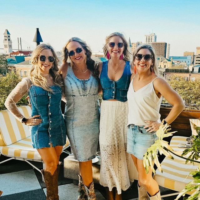 A group of four women posing for a picture on a rooftop.