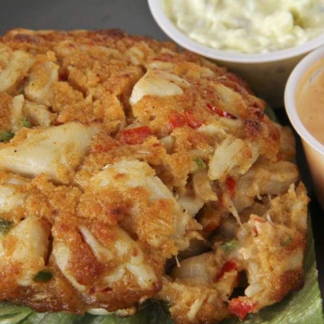 A lump crab cake with dipping sauces.