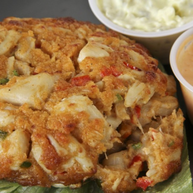 A lump crab cake with dipping sauces.