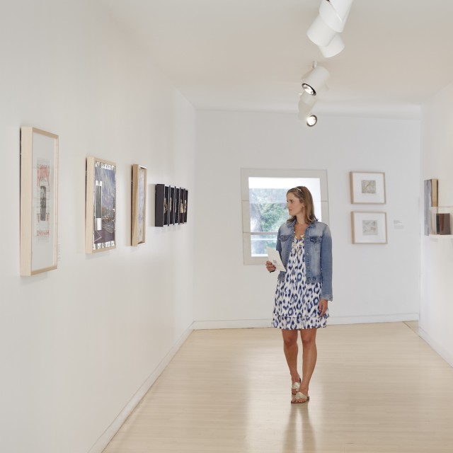 A woman walking and viewing an art gallery.