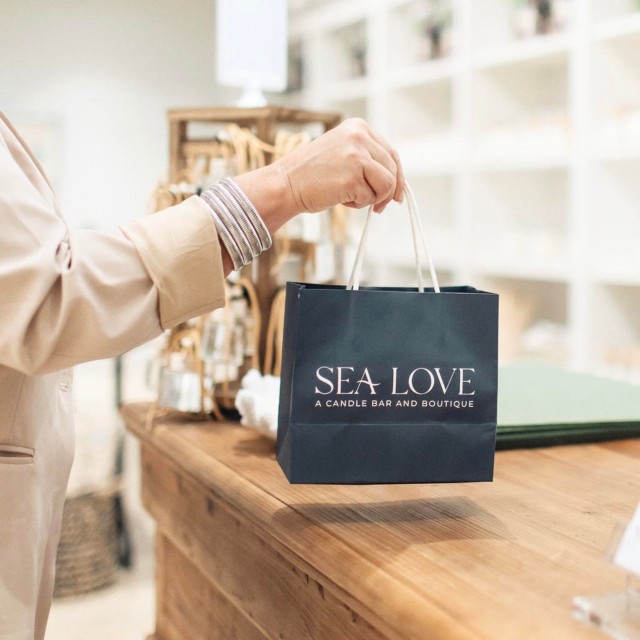 A person’s hand holding a navy blue gift bag in a store