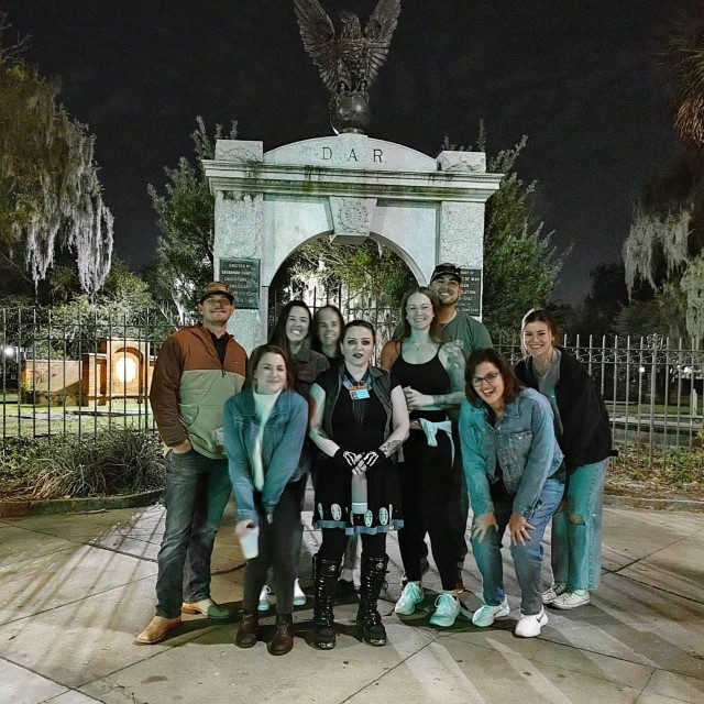 A group of people on a ghost tour in front of a cemetery.