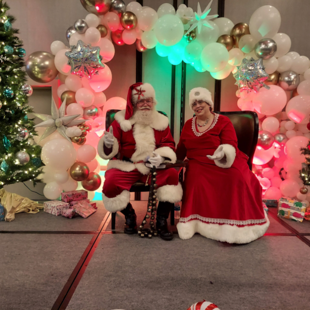 Santa and Mrs. Claus impersonators in front of a tree.