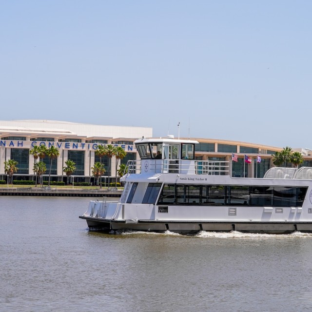 A ferry boat on the Savannah River passing a convention center.