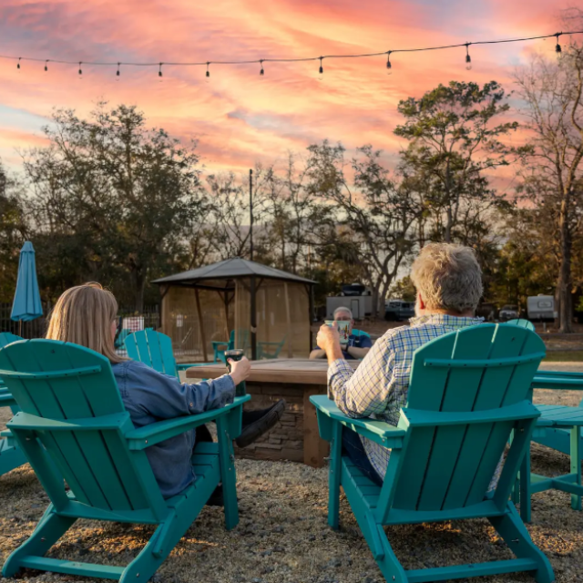 People sitting around a firepit at an RV and campground site.