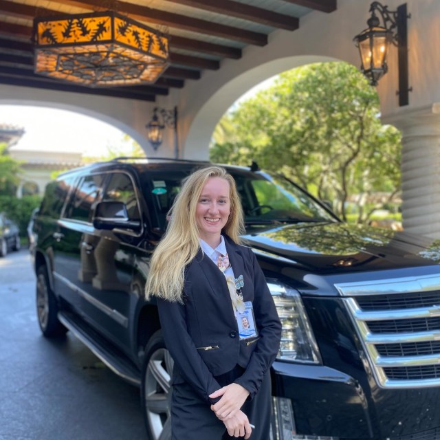 A chauffeur standing at a town car.