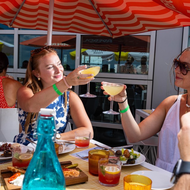 Two friends cheersing with cocktails at a rooftop bar.