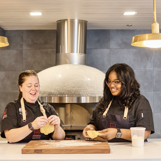 Two culinary students shaping dough.