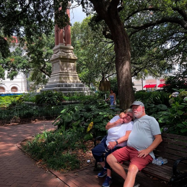 An older couple sitting on a bench in a square in Savannah, GA.