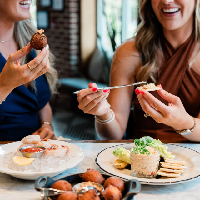 Two women dining and laughing together over brunch.