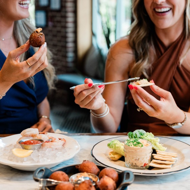 Two women dining and laughing together over brunch.
