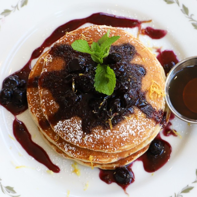 Lemon pancakes top with blueberry compote, served in a white dish.