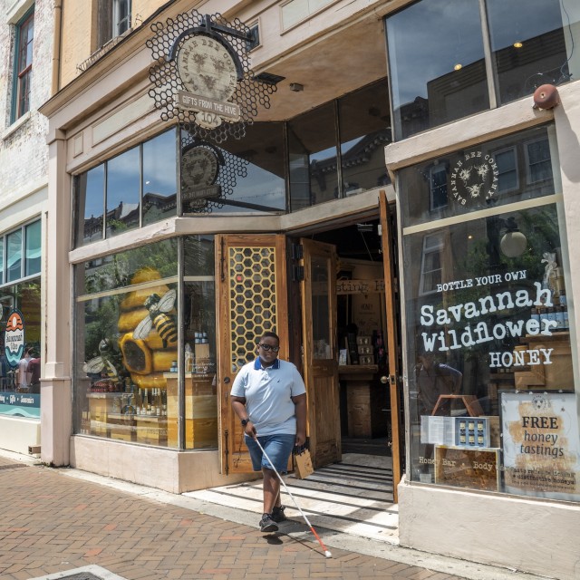 A blind man walking out of a local store in Savannah, GA.