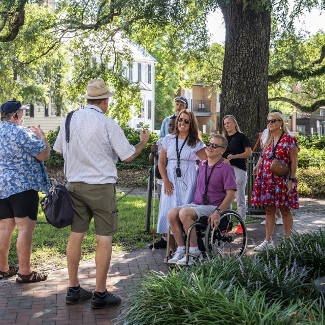 Wheelchair user with group in a square during an outdoor tour in Savannah, GA.