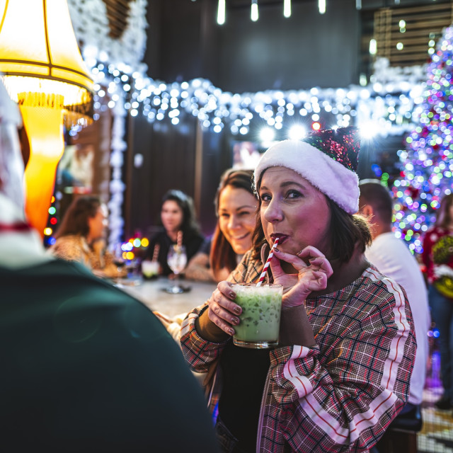A young woman sipping a holiday-themed drink in Perry Lane’s Wayward Bar.