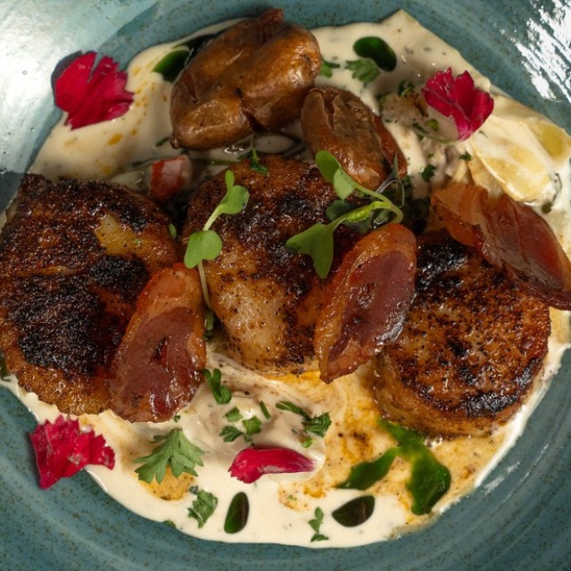 Seared diver scallops with shrimp, pancetta and creamy sauce plated at Alligator Soul.