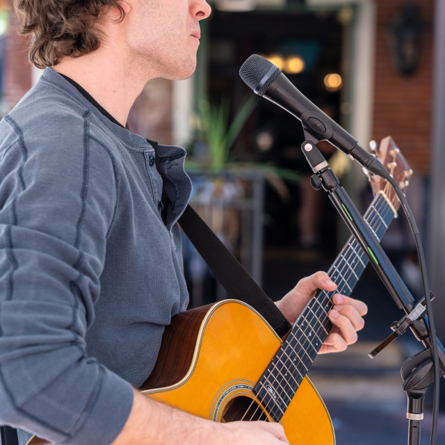 A musician plays a guitar during an outdoor concert.
