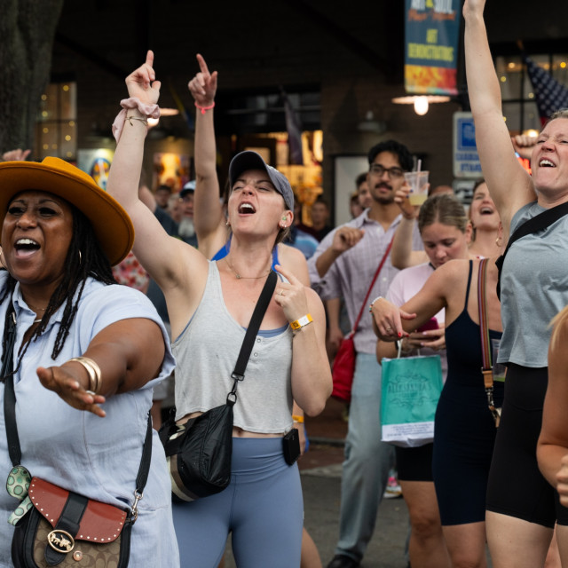 A crowd smiles and celebrates an outdoor concert.