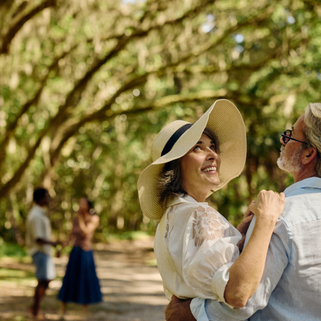 Couple embracing beneath moss-draped live oak trees in Savannah.