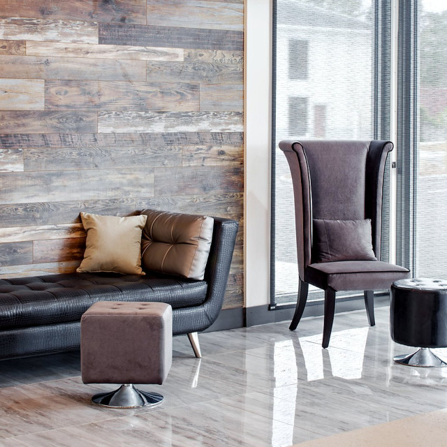 Contemporary lobby at Iris Garden Inn featuring a black leather sofa, gray accent chairs, wood-paneled walls and floor-to-ceiling windows.