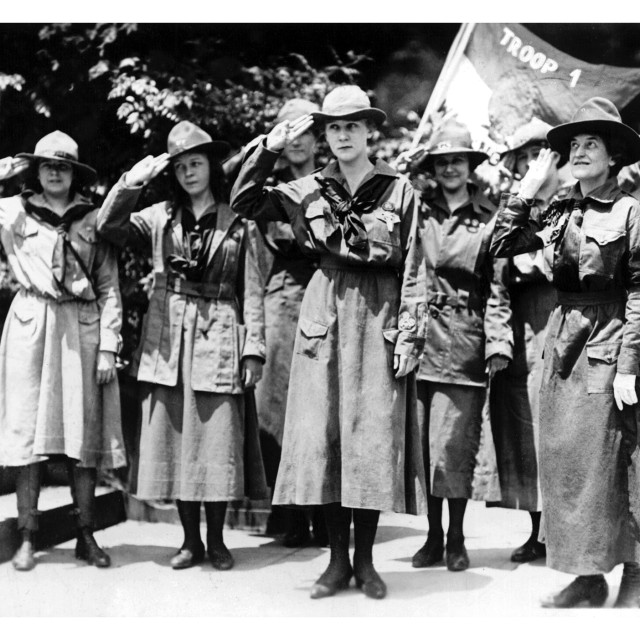 Historic Girl Scouts in uniform saluting during a troop ceremony in Savannah.