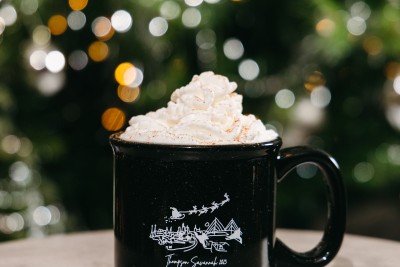 holiday Coquito cocktail with whipped cream in front of a christmas tree