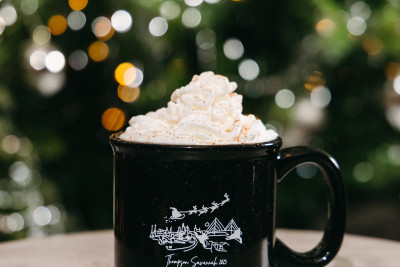 holiday Coquito cocktail with whipped cream in front of a christmas tree