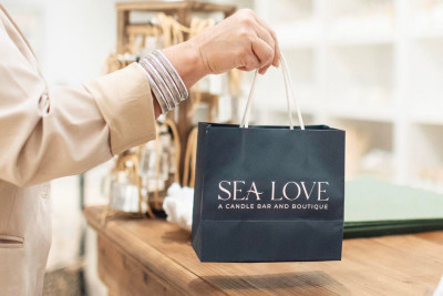 A person’s hand holding a navy blue gift bag in a store