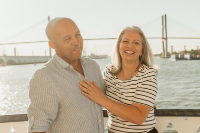 A couple posing for a photo on the outdoor deck of a riverboat.