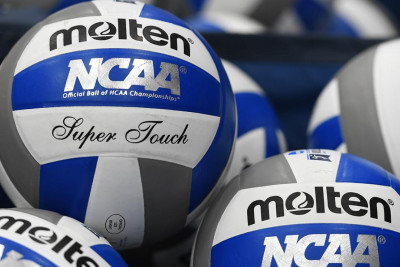 Numerous volleyballs piled together.