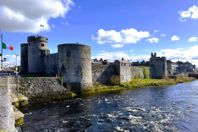 An exterior view of a historic castle surrounded by water in Limerick Ireland.