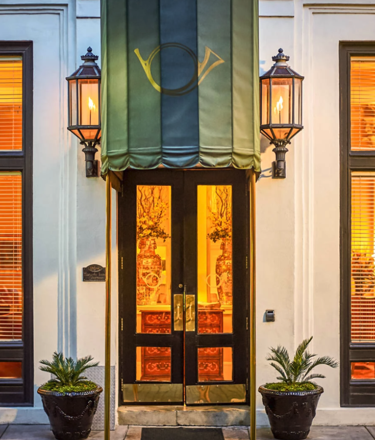 Exterior view of inn with green awning and oil lamps