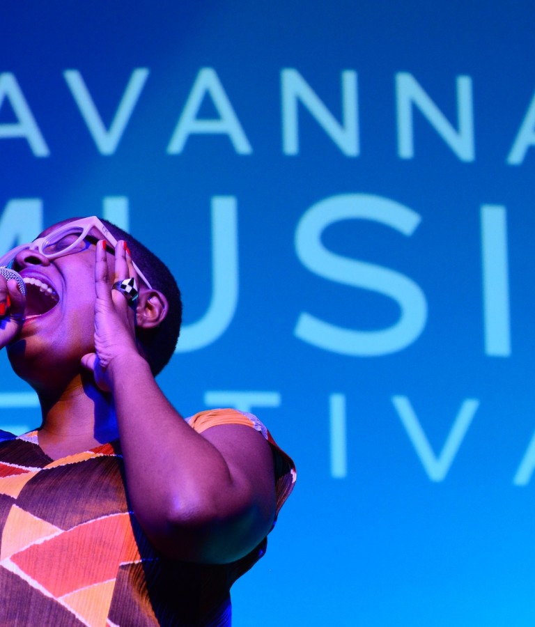 A young woman singing into a microphone on stage.
