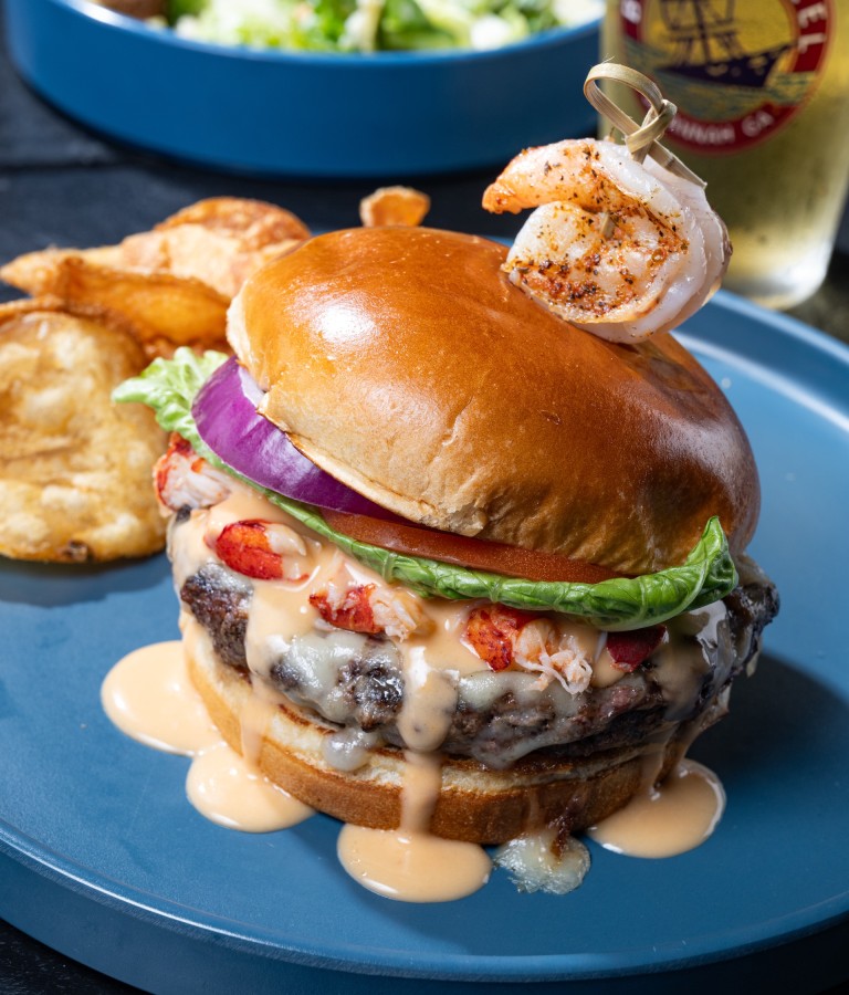 A burger served with chips, salad and a beer.