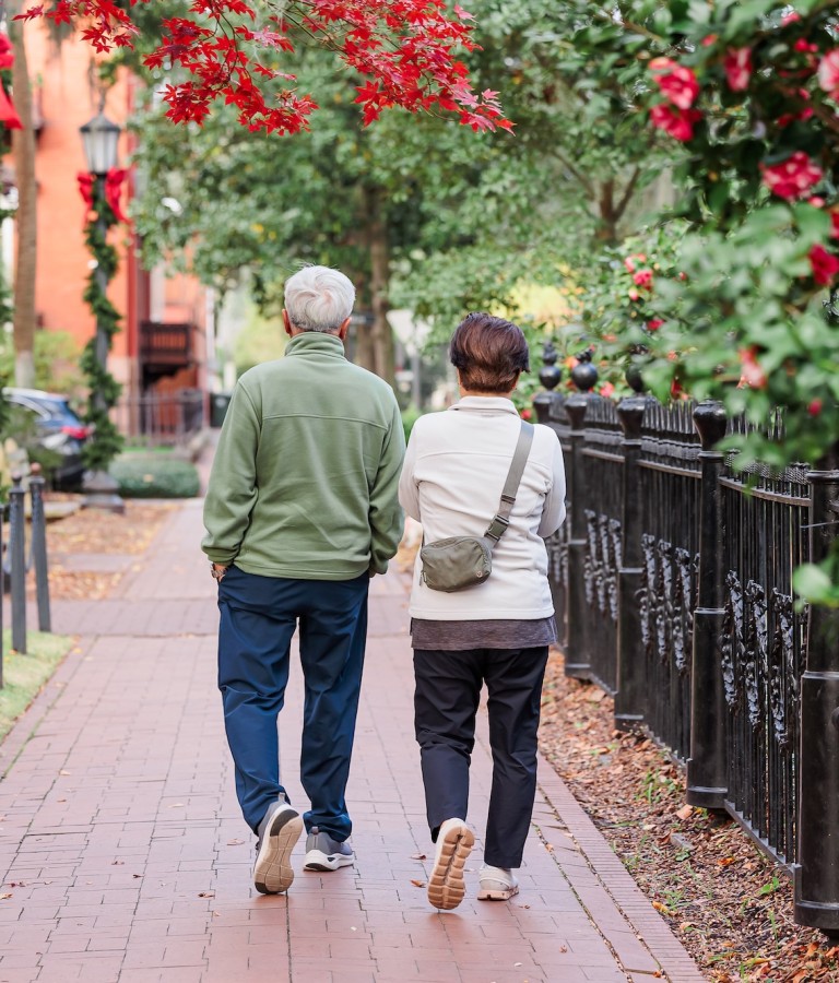 A couple walking down the sidewalk of downtown Savannah, GA in the winter.