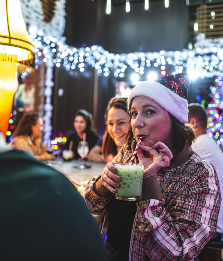 A young woman sipping a holiday-themed drink in Perry Lane’s Wayward Bar.