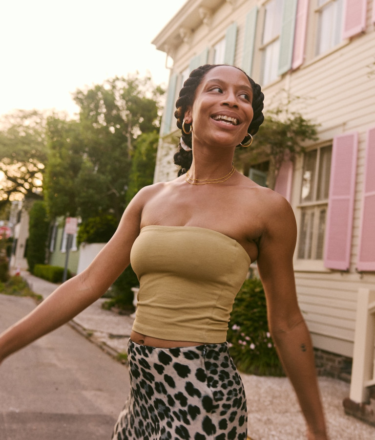 A woman walks past a historic Savannah home with pink shutters and a front porch.