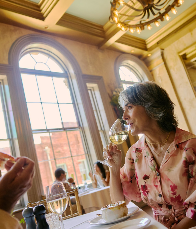 A couple dines in a romantic restaurant setting and sips white wine.