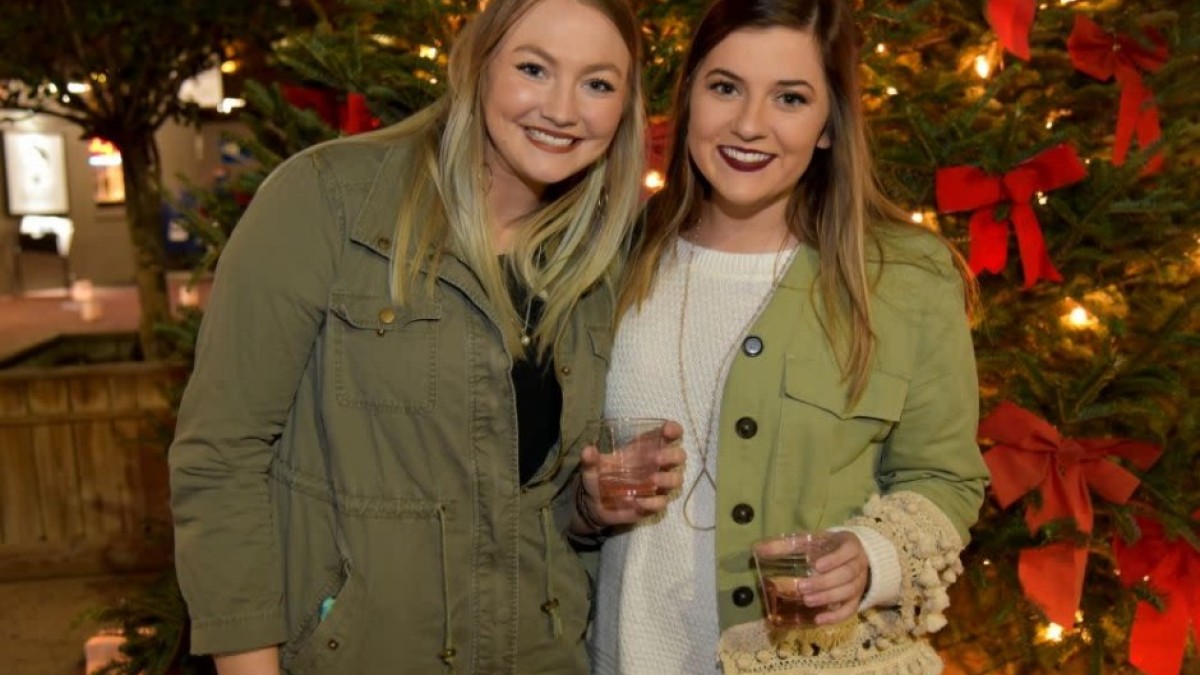 Two friend girls drinking wine at City Market’s holiday event