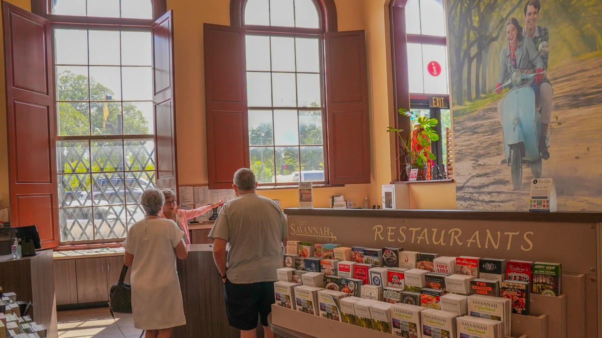 two visitors inside the visitor center with racks of brochures