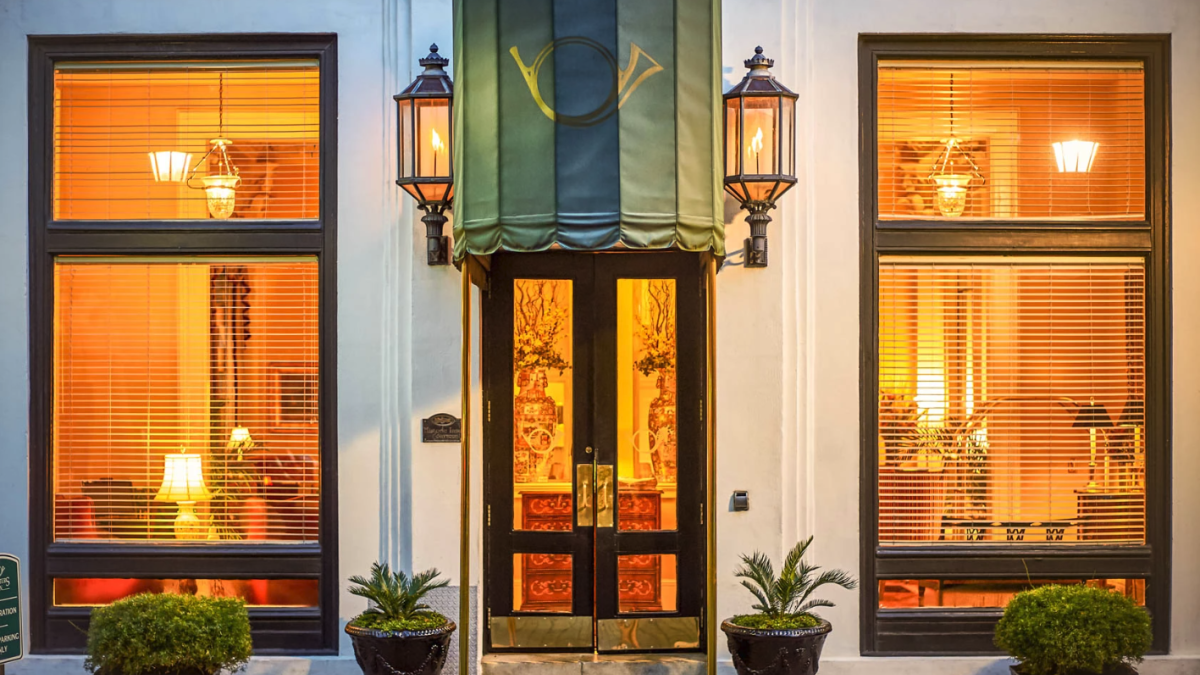 Exterior view of inn with green awning and oil lamps
