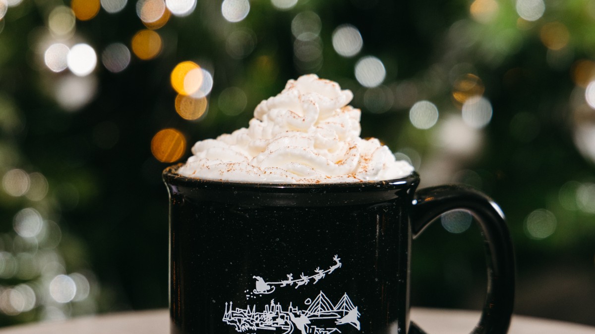 holiday Coquito cocktail with whipped cream in front of a christmas tree